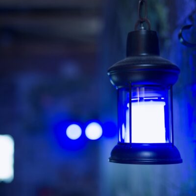 Lanterne bleue suspendue contre mur sombre